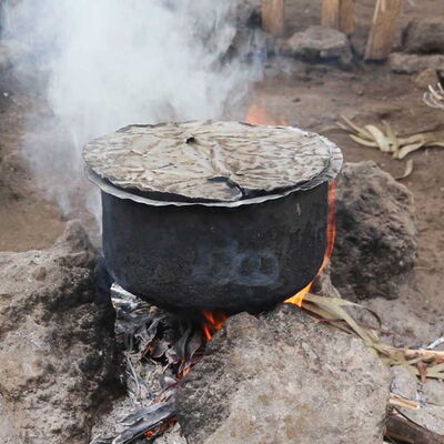Großer, verrußter Kochtopf auf offener Feuerstelle – Sinnbild für das notwendige Abkochen von Wasser für keimfreies Trinkwasser.