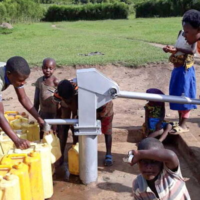 Menschen in Ruanda, die an einer Handpumpe sauberes Trinkwasser in Kanister füllen.